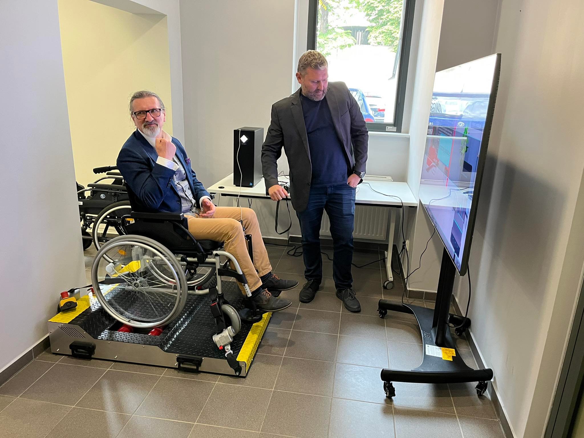 Adam Zwoliński z osobą testującą symulator wózka inwalidzkiego